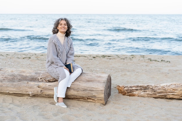 Senior vrouw op het strand met een boek