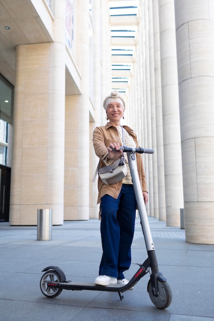 Senior vrouw poseren met een elektrische scooter in de stad