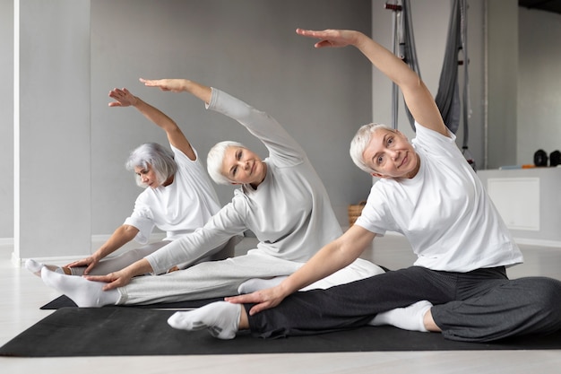 Gratis foto senior vrouwen die yoga-oefeningen doen in de sportschool op yogamatten