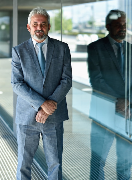 Senior zakenman met armen overschreden buiten het moderne kantoorgebouw.