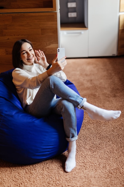 Sensuele vrouw in spijkerbroek en witte t-short maken selfie hebben een videocall op haar telefoon