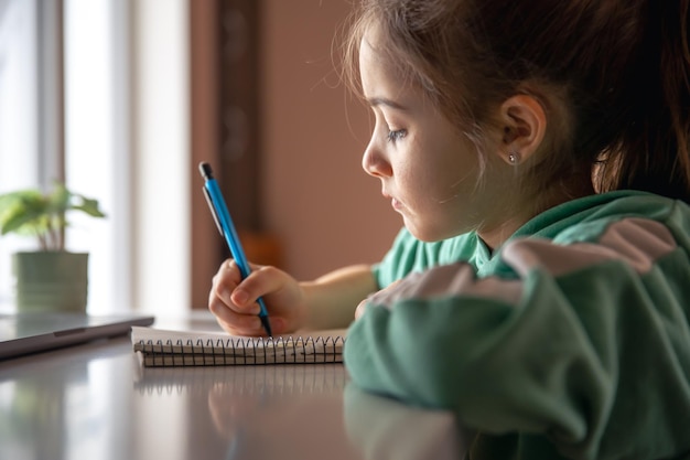 Gratis foto serieus klein meisje schrijft met een pen in een notitieboekje