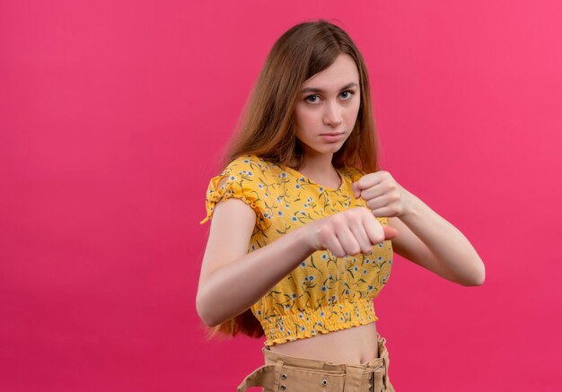 Serieus op zoek jong meisje doet boksgebaar op geïsoleerde roze ruimte met kopie ruimte