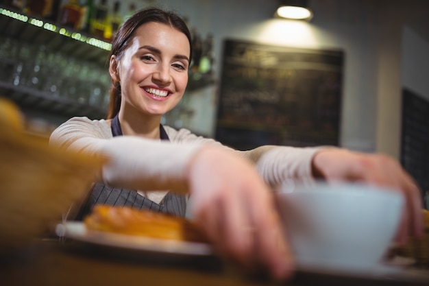 Serveerster serveren een kopje koffie aan de klant in cafÃ ©