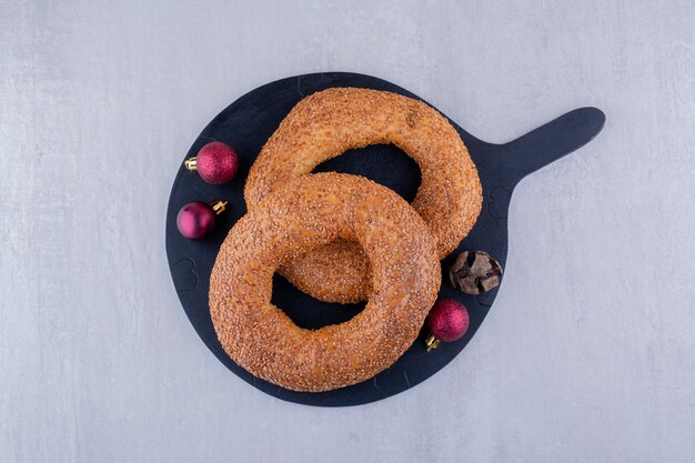 Sesam gecoate bagels op een zwarte bord op witte achtergrond.