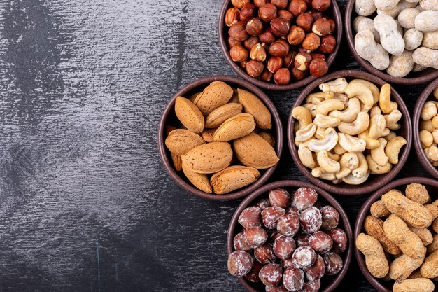 Set van pecannoten, pistachenoten, amandel, pinda, cashewnoten, pijnboompitten en diverse noten en gedroogde vruchten in verschillende mini-kommen