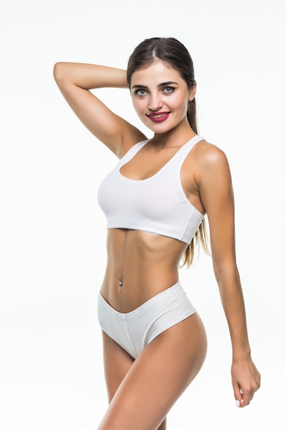 Sexy jonge geïsoleerde vrouw in wit ondergoed op witte muur