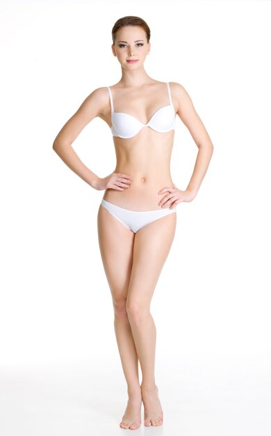 Sexy jonge slanke vrouw met mooi perfect lichaam poseren op witte ruimte. Portret van volledige lengte