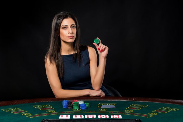 Sexy vrouw met pokerkaarten en chips. Vrouwelijke speler in een prachtige zwarte jurk