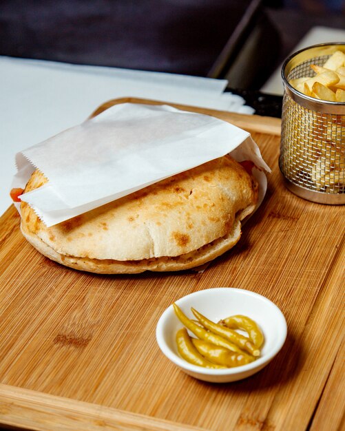 Shaurma geserveerd op snijplank met friet en gepekelde peper