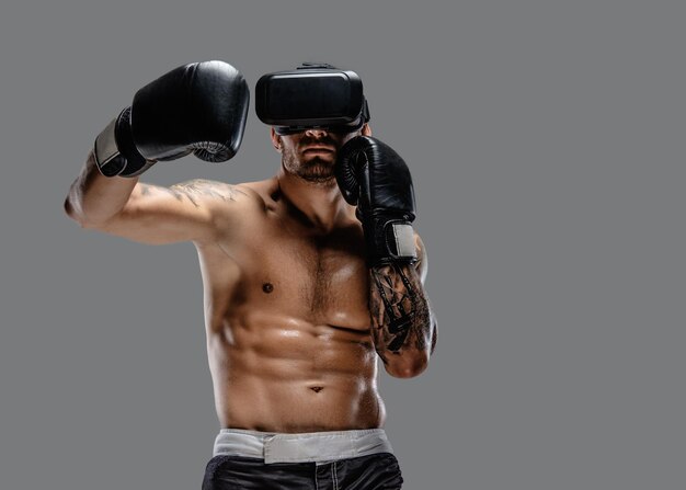 Shirtless brutale boksvechter in virtual reality-bril op zijn hoofd. Geïsoleerd op een grijze achtergrond.
