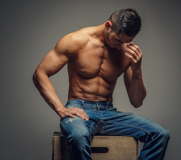 Gratis foto shirtless gespierde man in denim jeans. geïsoleerd op grijze achtergrond.