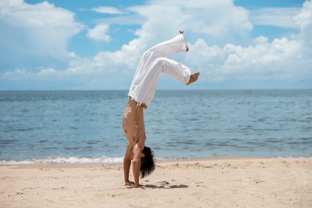 Gratis foto shirtloze man die alleen capoeira beoefent op het strand