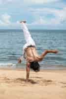 Gratis foto shirtloze man die alleen capoeira beoefent op het strand
