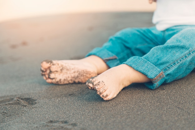 Gratis foto shoeless voeten van babyzitting op zand