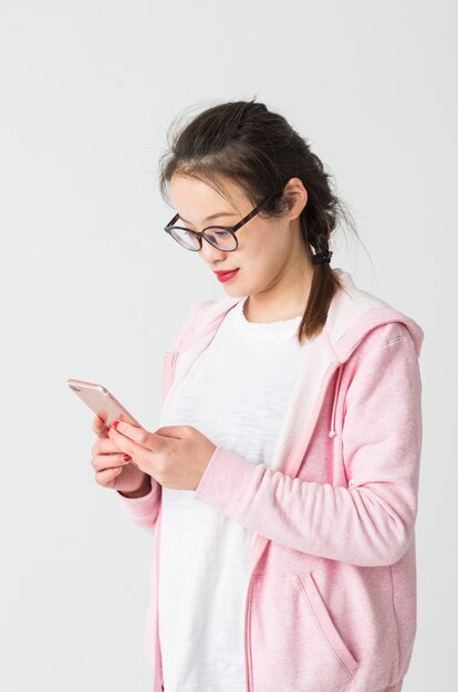 Shot in de studio van de jonge Aziatische vrouw die mobiele telefoon speelt