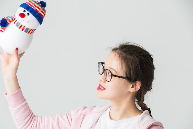 Shot in de studio van de jonge aziatische vrouw met een kerstman sneeuwpop