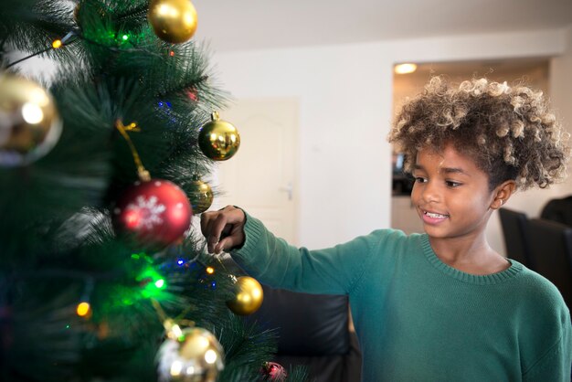 Shot van een Afro-Amerikaans meisje met krullend haar kerstboom in de woonkamer versieren