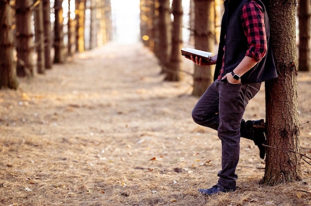 Gratis foto shot van een man met een boek poserend in een bos