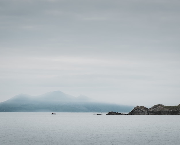 Gratis foto shot van een meer en kliffen, mistige bergen