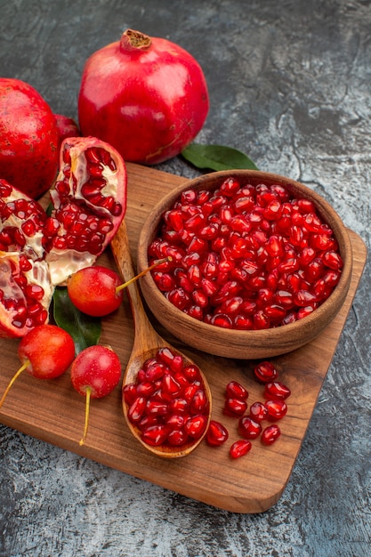 Side close-up view fruit de snijplank met granaatappel zaden lepel kersen granaatappel