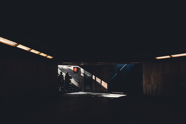 Silhoette van twee mensen die een donker schaduwrijk ondergronds gebouw binnengaan