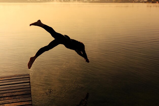 Silhouet van actieve sportman die in mistig meer stormt