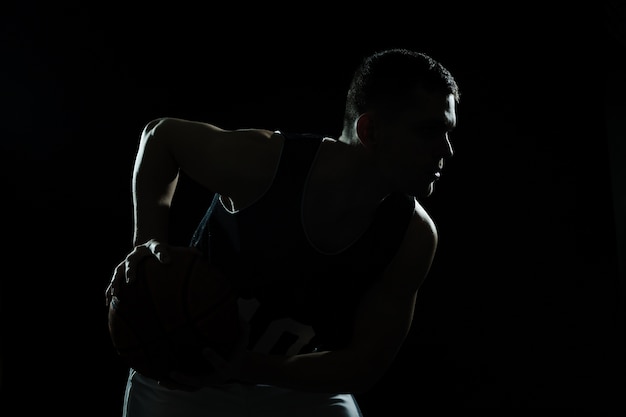 Silhouet van basketbal speler die de bal op zwarte achtergrond