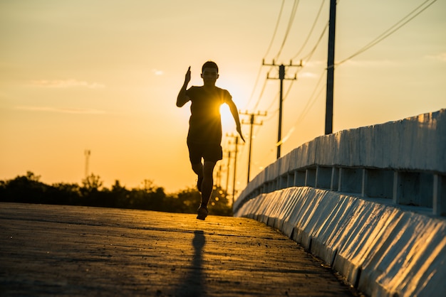 silhouet van een jonge fitness man loopt op zonsopgang