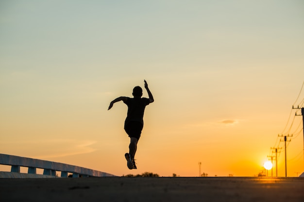 silhouet van een jonge fitness man loopt op zonsopgang