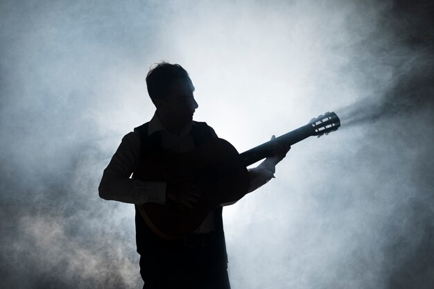 Silhouet van een muzikant op het podium gitaar spelen