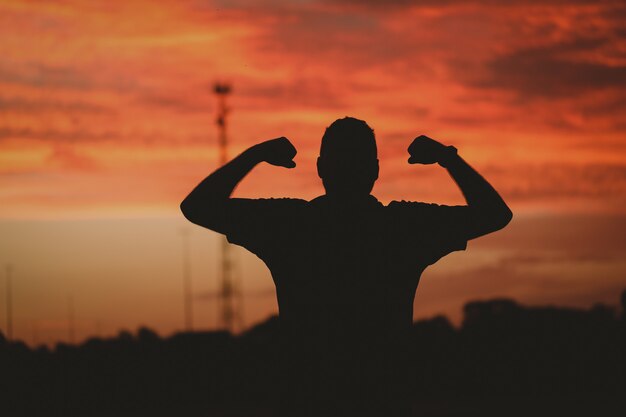 Silhouet van een sterke man onder een bewolkte hemel tijdens de gouden zonsondergang