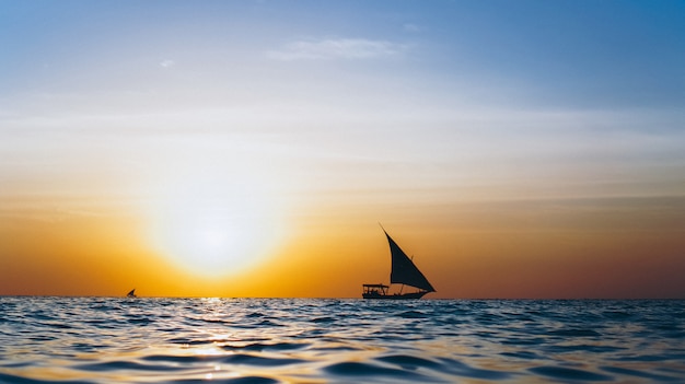 Silhouet van jacht in de open oceaan op de zonsondergang