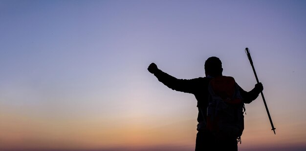 Silhouet van juichende wandelende man met open armen naar de zonsopgang staan op de berg met kopieerruimte Reizen Lifestyle reislust avontuur concept zomervakanties buiten