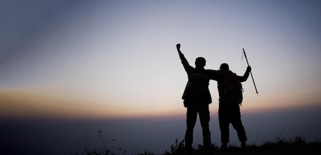 Silhouet van juichende wandelende mannen open armen naar de zonsopgang op de berg Reizen Lifestyle reislust avontuur concept zomervakanties buiten