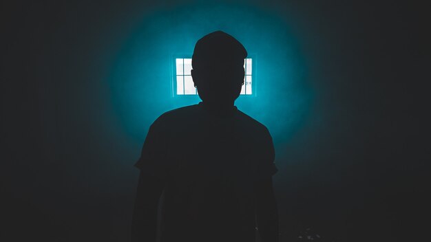 Silhouet van staande persoon in een donkere kamer