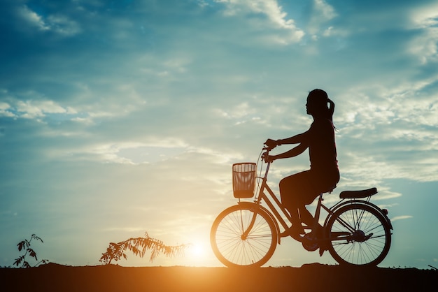 Silhouet van vrouwen met fiets en mooie hemel