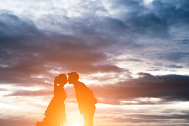 Silhouet van zoete paar kussen over zonsondergang achtergrond.
