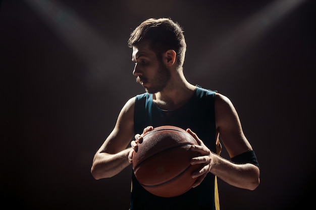 Silhouetmening van een bal van de de holdingsmand van de basketbalspeler op zwarte