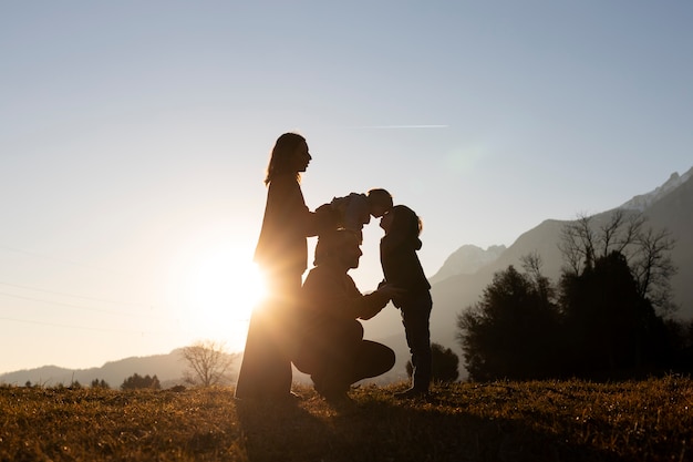 Gratis foto silhouetten van gezinnen in de natuur bij zonsondergang