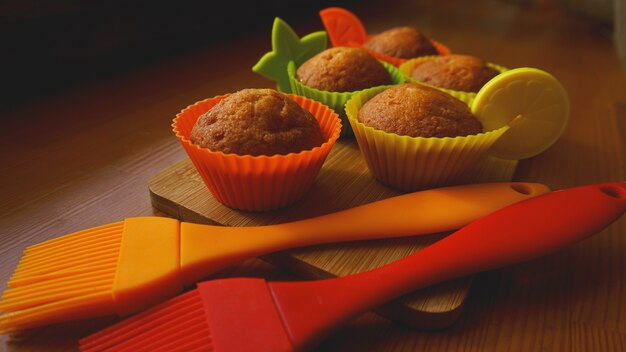 Simpele mini muffins in kleurrijke siliconen bakvormen. siliconen cup cupcakes en siliconen kwasten bakken. keuken en kookconcept op houten achtergrond
