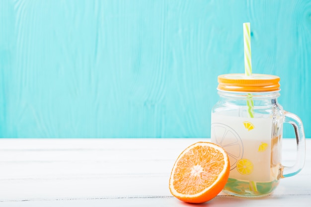 Sinaasappel dichtbij glas met stro en limonade