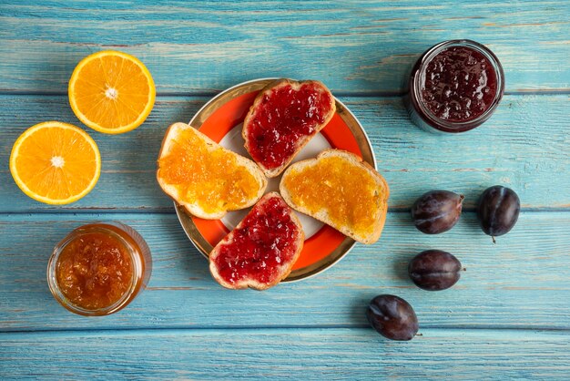 Sinaasappel- en pruimconfituur in een glazen pot en op de toastbroodjes in een bord.