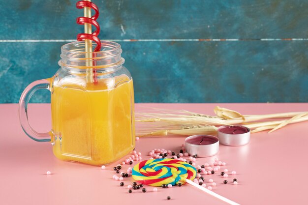 Sinaasappelsap in een glazen pot met popsicle rond