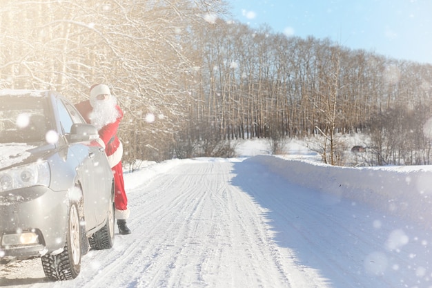 Sinterklaas komt met cadeautjes van buiten. kerstman in een rood pak met een baard en het dragen van een bril loopt langs de weg naar kerstmis. kerstman brengt geschenken aan kinderen.