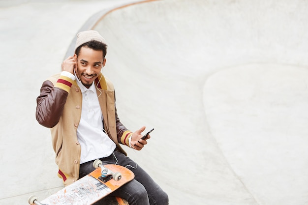 Skateboarden concept. Stijlvolle, zorgeloze tiener skateboarden, rust uit na een actieve dag,