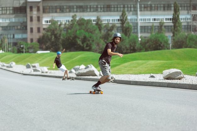 Skateboarders doen op zonnige dagen een truc in de straat van de stad