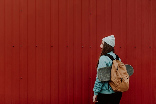 Gratis foto skatermeisje in de stedelijke holdingsrugzak en skate