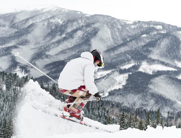 Skiër die ski-uitrusting draagt en tijd doorbrengt op berghellingen in het winterseizoen