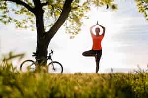 Gratis foto slank mooie vrouw silhouet sport in de ochtend in park doet yoga
